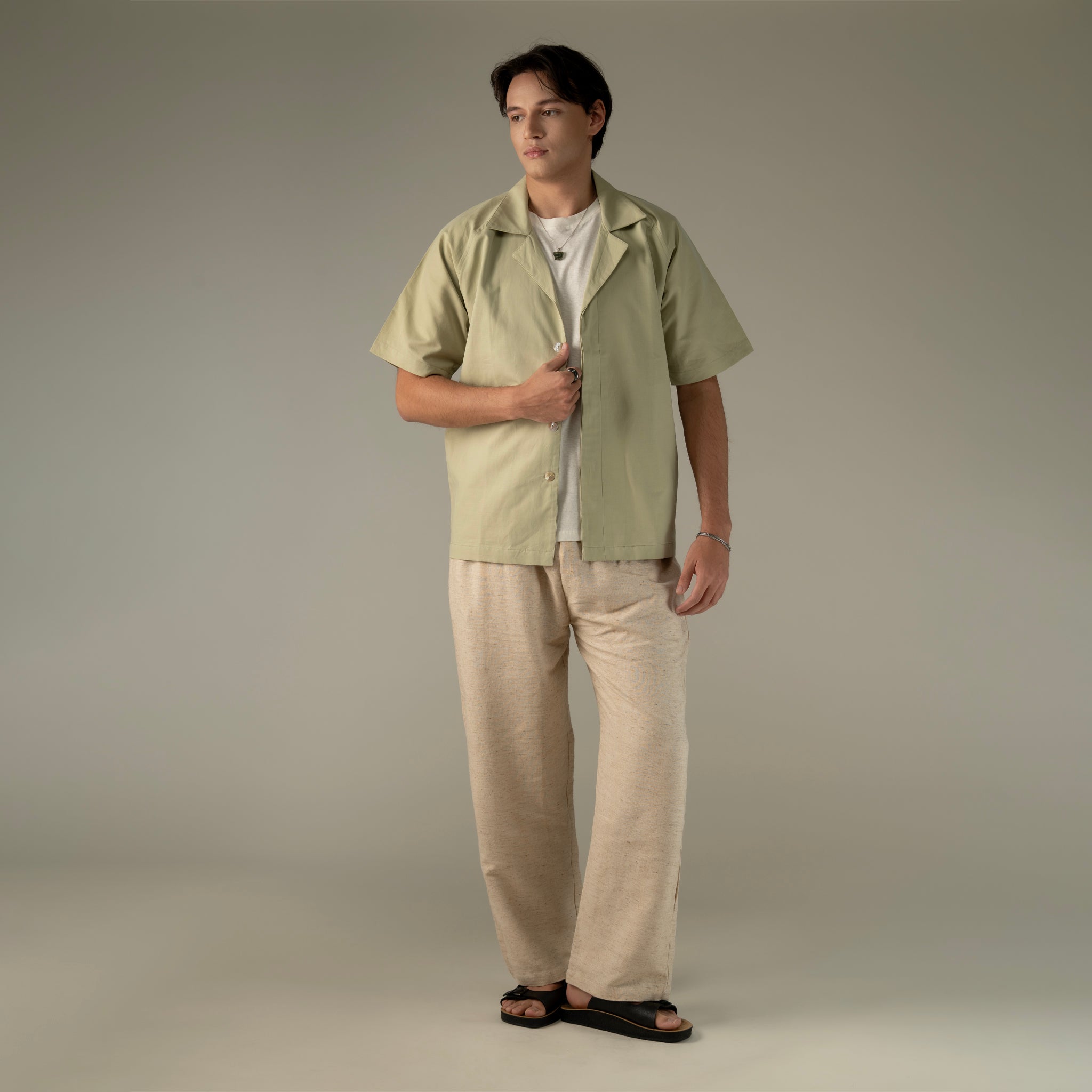 Man wearing a light green shirt and beige pants against a neutral background